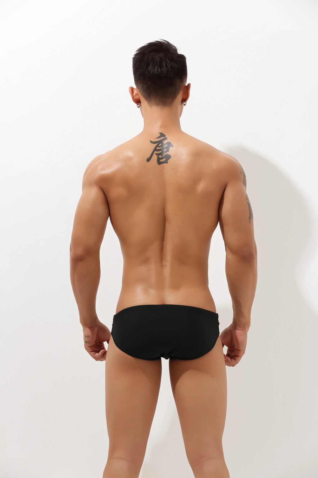 Black 4inme low-rise cutout swim brief with side cutouts, featuring a sleek, modern design on a plain background.