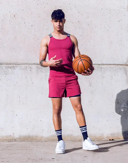 Red Supawear SPR Max athletic shorts by CITYBOYZ★USA, shown in a tank top with a gallery-style background.